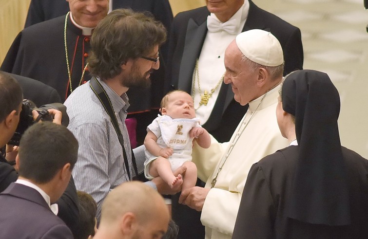 Aula Paolo VI, 11 gennaio 2016: convegno Cei per il 25° del Settore per la catechesi delle persone disabili - Papa Francesco benedice un neonato con il papà